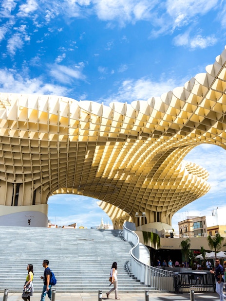 Metropol Parasol wooden structure in Plaza de la Encarnación, Seville, Spain, with people walking below.