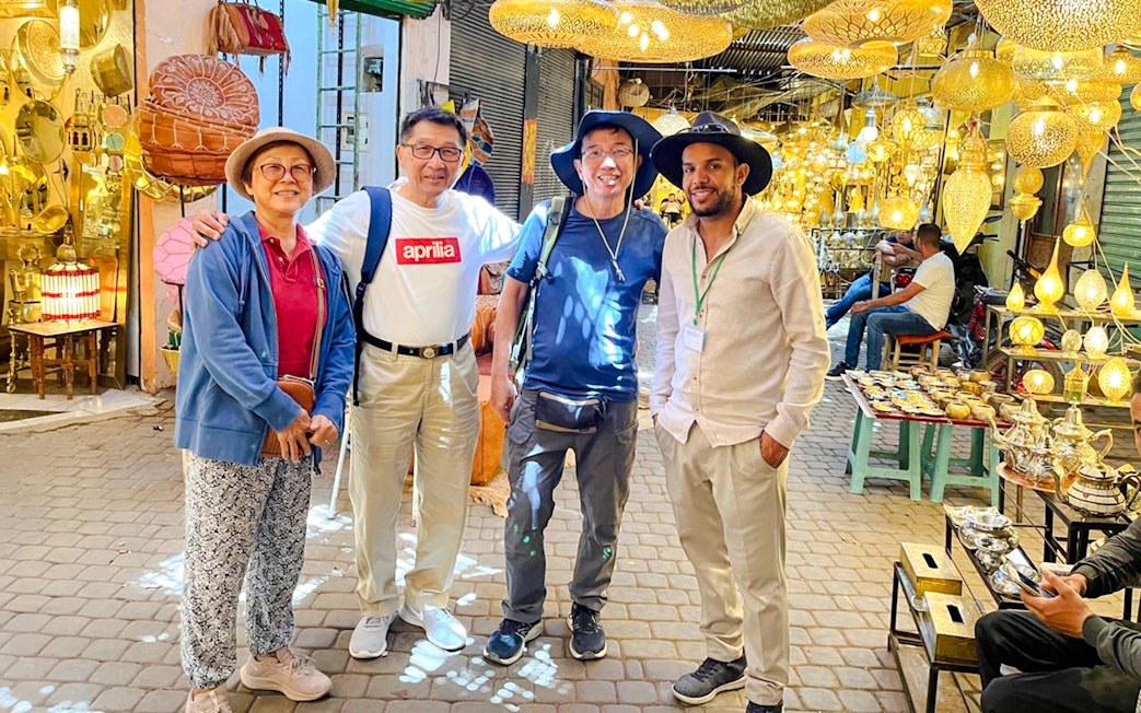 Tourists with guide exploring a lantern shop in Marrakesh souk, Morocco.