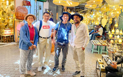Tourists with guide exploring a lantern shop in Marrakesh souk, Morocco.