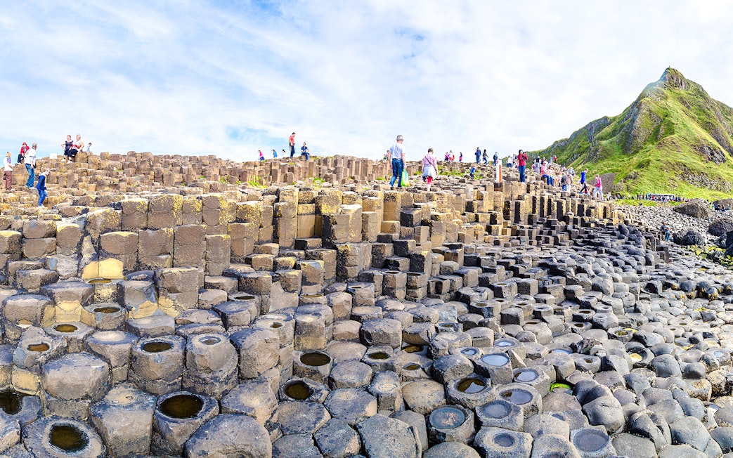Visitors exploring basalt columns at Giant's Causeway, Northern Ireland.