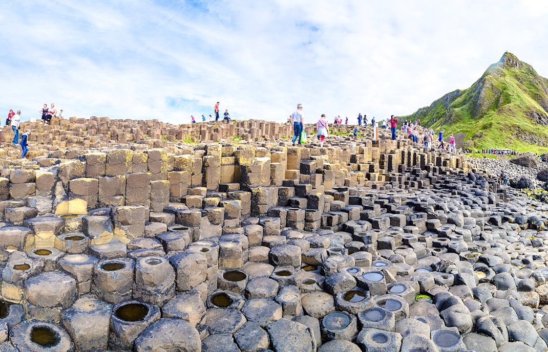 Visitors exploring basalt columns at Giant's Causeway, Northern Ireland.