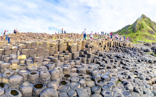 Visitors exploring basalt columns at Giant's Causeway, Northern Ireland.
