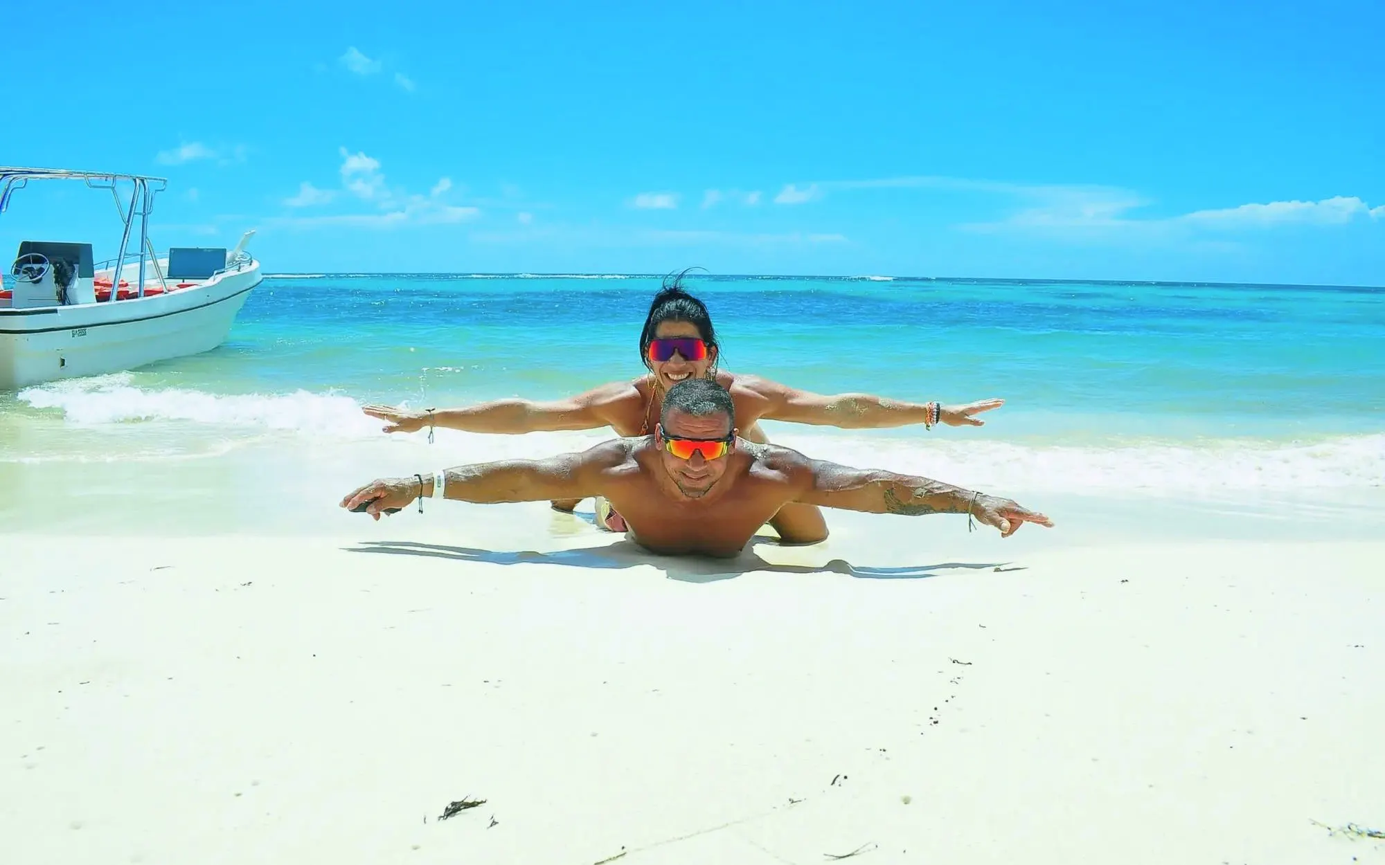 Couple enjoying the beach on Saona Island with a boat in the background.