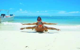 Couple enjoying the beach on Saona Island with a boat in the background.