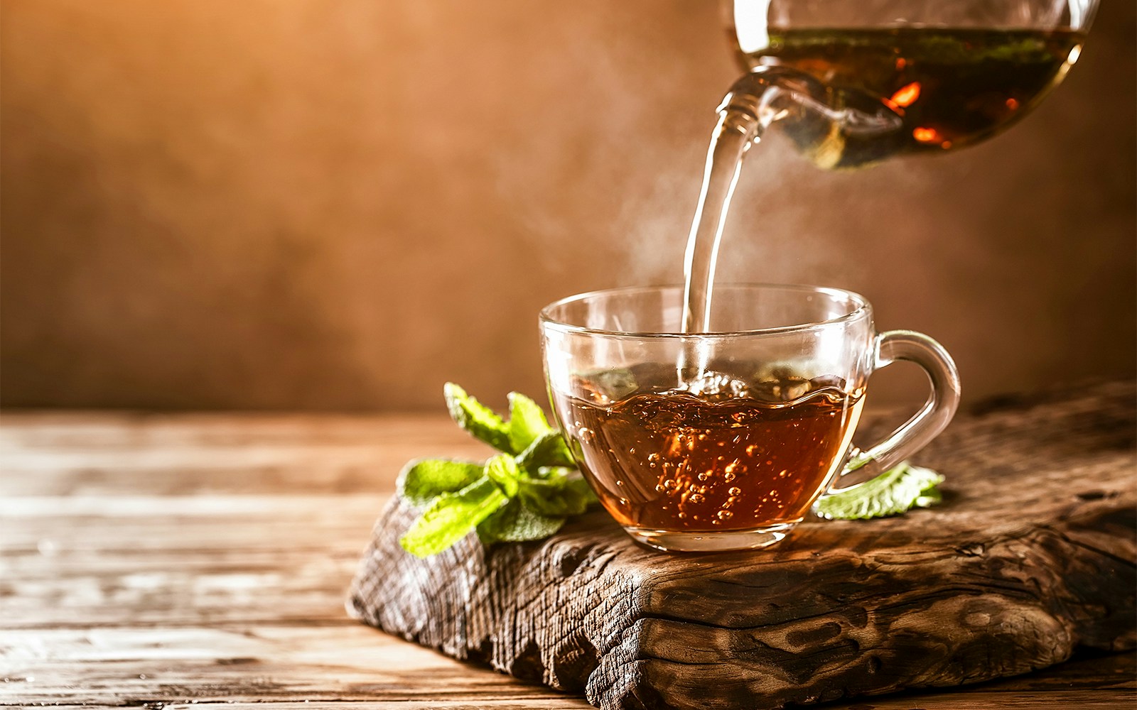 Tea being poured into a glass cup on a wooden table, Daintree National Park.