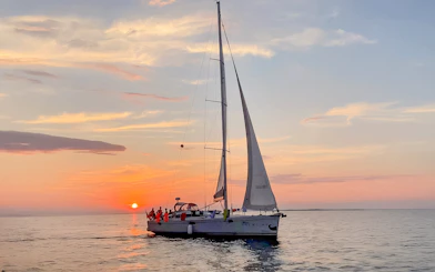Sailboat on Gdansk River during sunset cruise with vibrant sky.