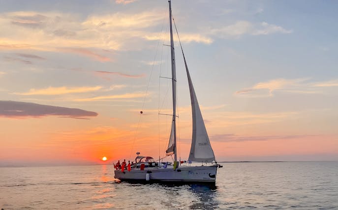 Sailboat on Gdansk River during sunset cruise with vibrant sky.