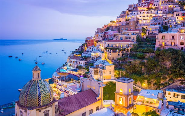 Sorrento coastline with colorful hillside buildings and sea view at dusk.
