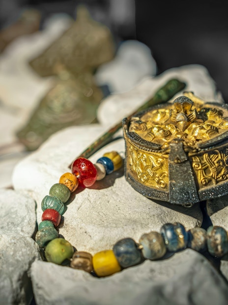 Viking artifacts including a gold brooch and beaded necklace at a museum in Stockholm, Sweden.