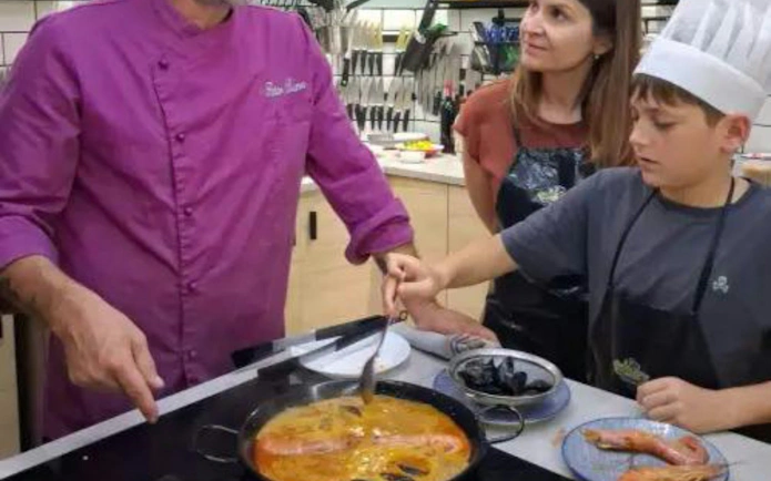 Cooking class participants making paella in Barcelona kitchen.
