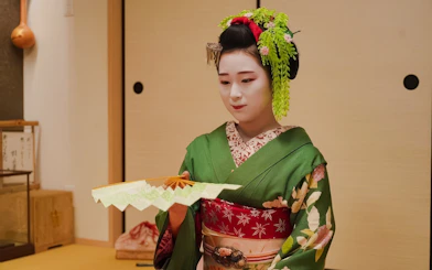 Geisha in traditional attire holding a fan during Gion Walking Tour in Kyoto.