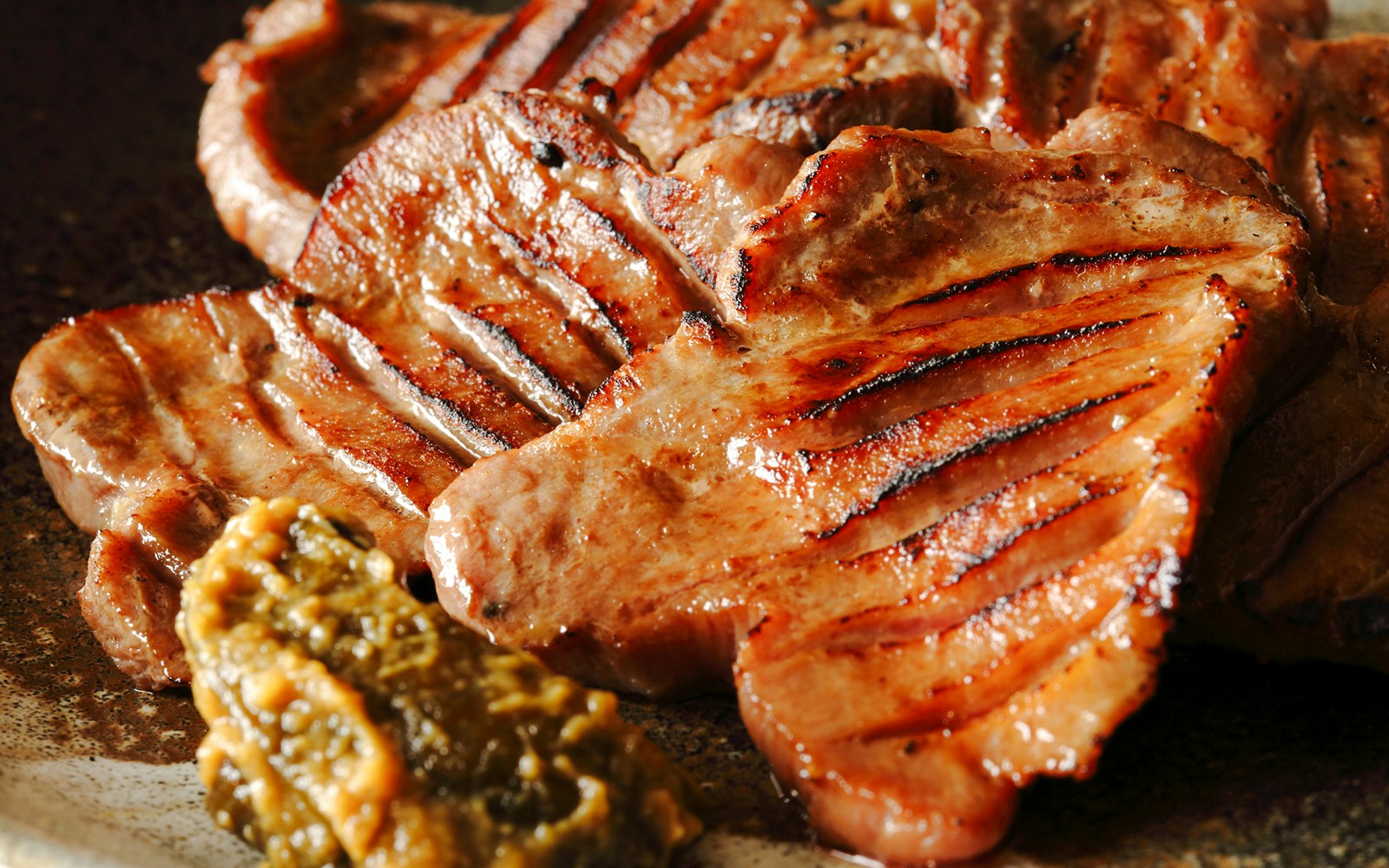 Grilled chicken with char marks served with a side of green relish.