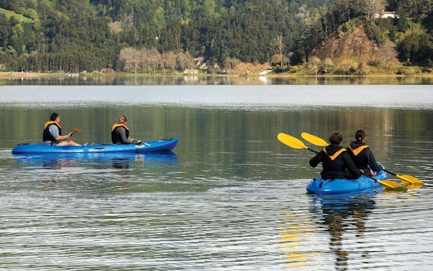 People kayaking on a lake surrounded by lush greenery in Furnas.