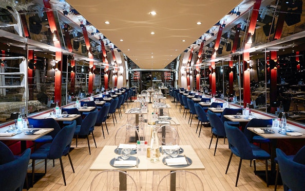 Seine River dinner cruise interior with tables set for an Italian menu experience.