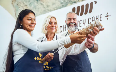 Participants making chimney cake at a Budapest workshop.