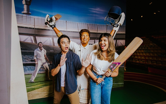 Sachin Tendulkar wax figure with visitors at Madame Tussauds Singapore.
