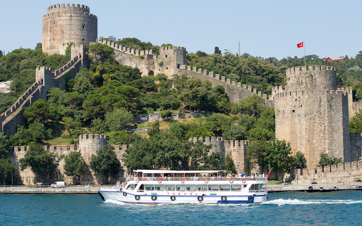 Cruise boat on Bosphorus passing Rumeli Fortress in Istanbul, Turkey.
