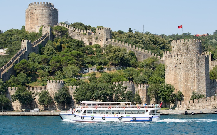Cruise boat on Bosphorus passing Rumeli Fortress in Istanbul, Turkey.