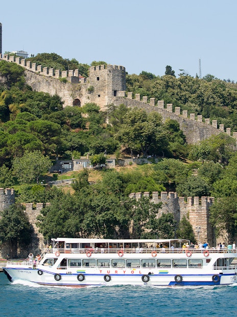 Cruise boat on Bosphorus passing Rumeli Fortress in Istanbul, Turkey.