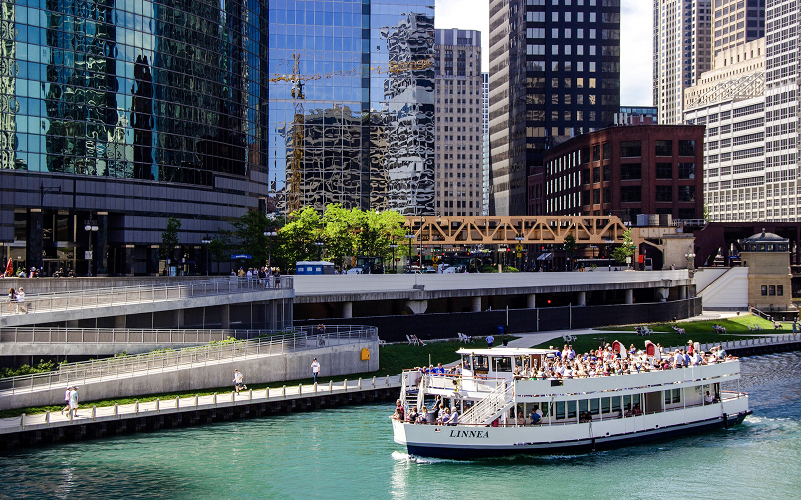 Tour boat on Chicago River with city skyscrapers in the background.