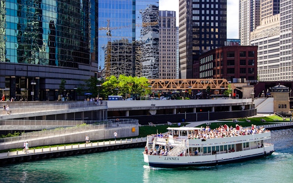 Tour boat on Chicago River with city skyscrapers in the background.
