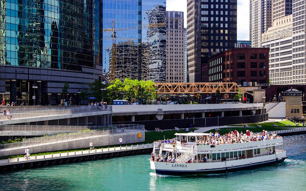 Tour boat on Chicago River with city skyscrapers in the background.