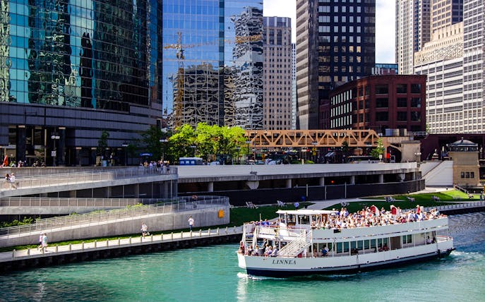 Tour boat on Chicago River with city skyscrapers in the background.
