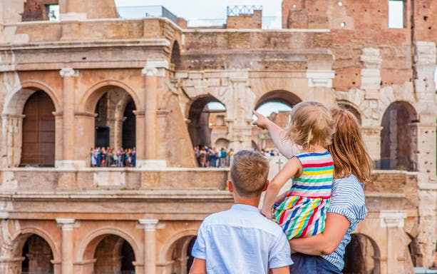 Family exploring the Colosseum in Rome, child pointing at ancient arches.