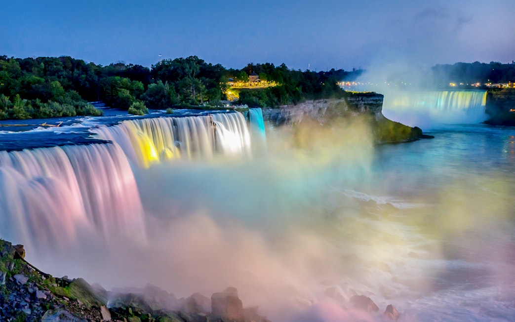 Niagara Falls illuminated at night with colorful lights and mist.