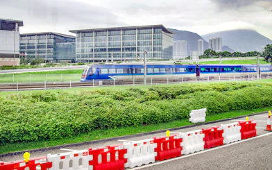 Train traveling between Hong Kong International Airport and city with modern buildings in background.