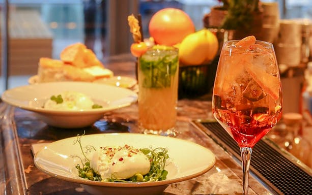 Dinner setting with burrata salad and cocktails at The Larch, Sky Garden London.