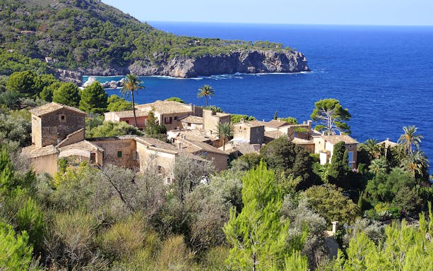 Valldemossa village with stone houses and lush greenery overlooking the Mediterranean Sea.