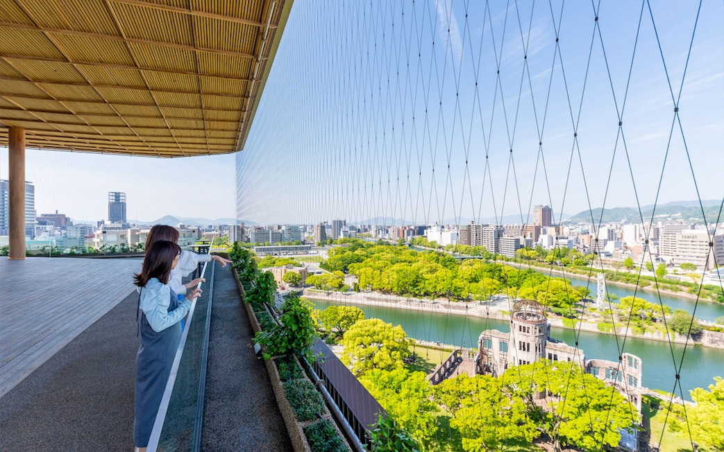 Visitors enjoying the view from Hiroshima Orizuru Tower overlooking the Atomic Bomb Dome and cityscape.