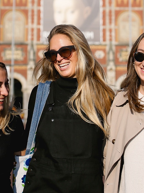 Three people smiling in front of the Rijksmuseum in Amsterdam during a professional photoshoot.