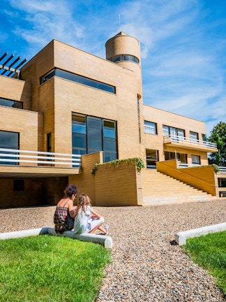Visitors sitting outside Villa Cavrois, a modernist architectural landmark in France.