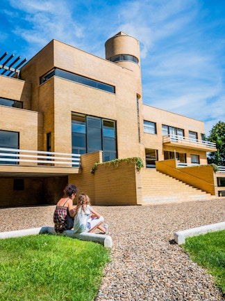 Visitors sitting outside Villa Cavrois, a modernist architectural landmark in France.