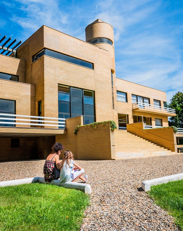 Visitors sitting outside Villa Cavrois, a modernist architectural landmark in France.