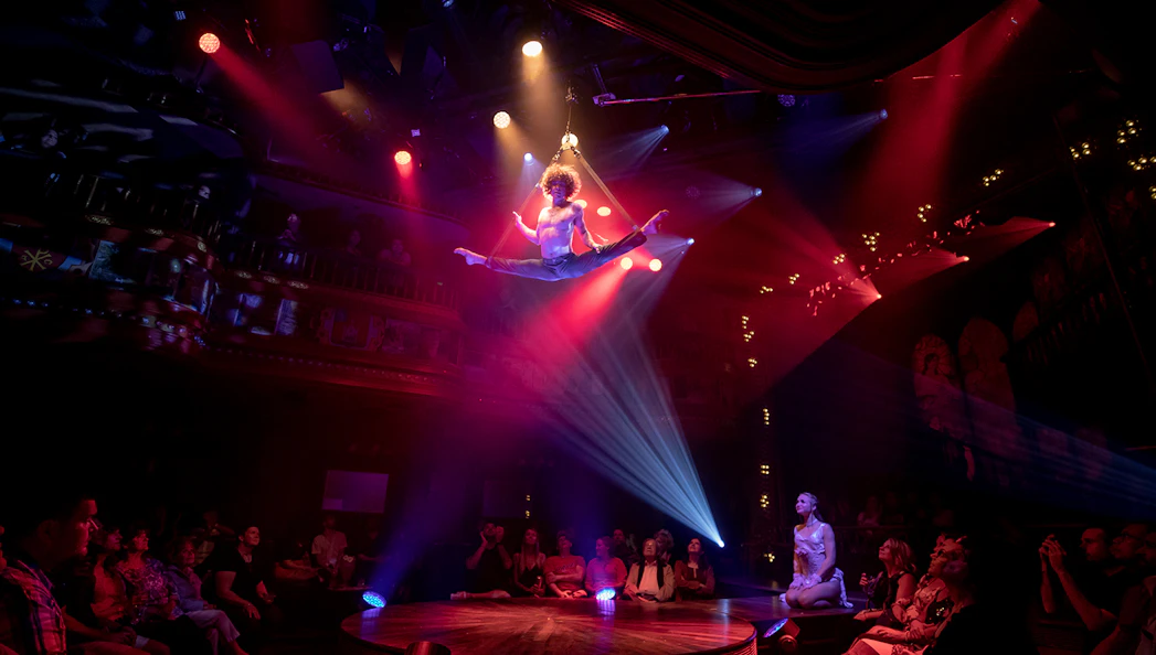 Aerial performer at Atomic Saloon Show in Las Vegas, mid-air split under stage lights.