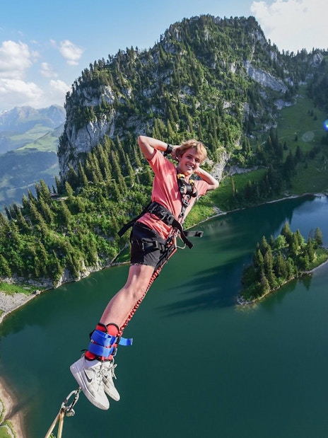 Bungee jumper over Stockhorn Interlaken with alpine lake and mountains in view.
