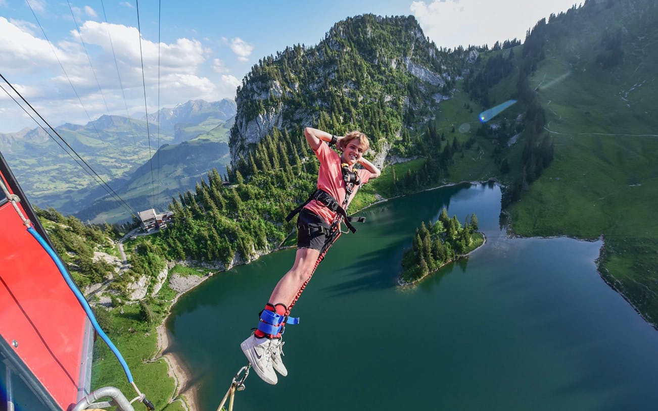 Bungee jumper over Stockhorn Interlaken with alpine lake and mountains in view.