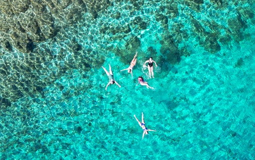 People swimming in clear turquoise waters near Brac Island's secluded bays.