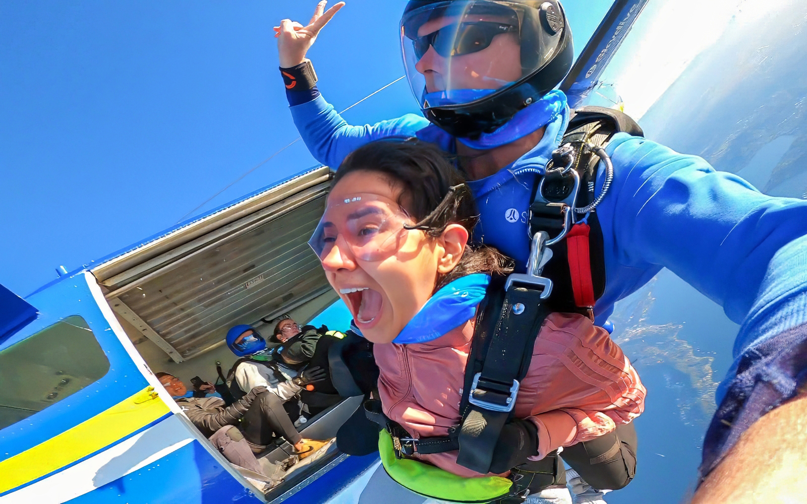 Tandem skydiving over Newcastle, Australia with woman and instructor exiting plane.