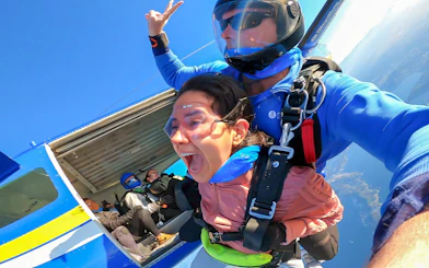 Tandem skydiving over Newcastle, Australia with woman and instructor exiting plane.