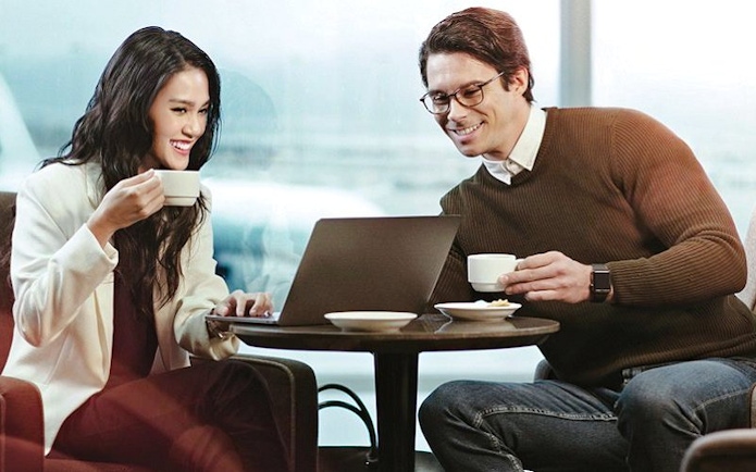 People enjoying coffee and working on a laptop at Plaza Premium Lounge, King Abdulaziz International Airport.