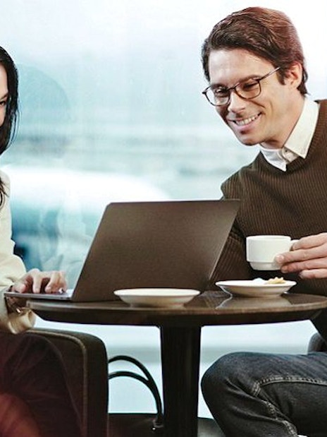 People enjoying coffee and working on a laptop at Plaza Premium Lounge, King Abdulaziz International Airport.
