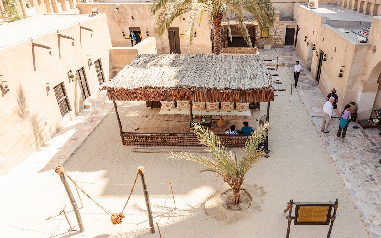 Traditional courtyard in Dubai with visitors and a shaded seating area.