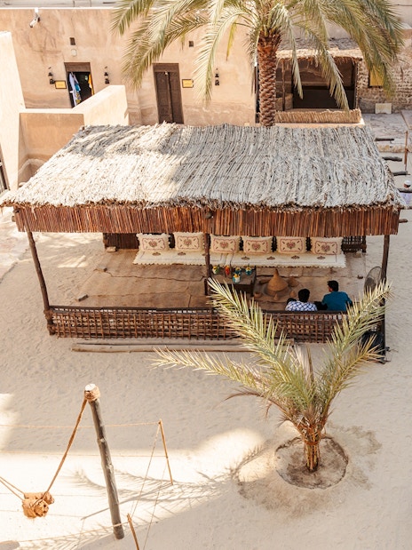Traditional courtyard in Dubai with visitors and a shaded seating area.