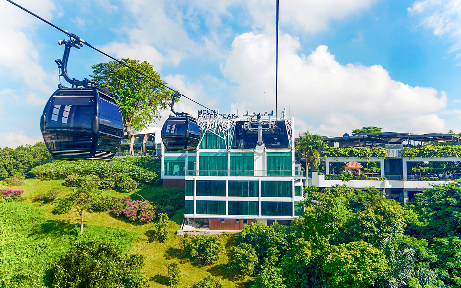 Cable cars over Mount Faber Peak, Singapore, with lush greenery and skyline.