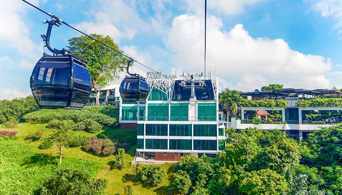 Cable cars over Sentosa Island with Singapore skyline in the background.