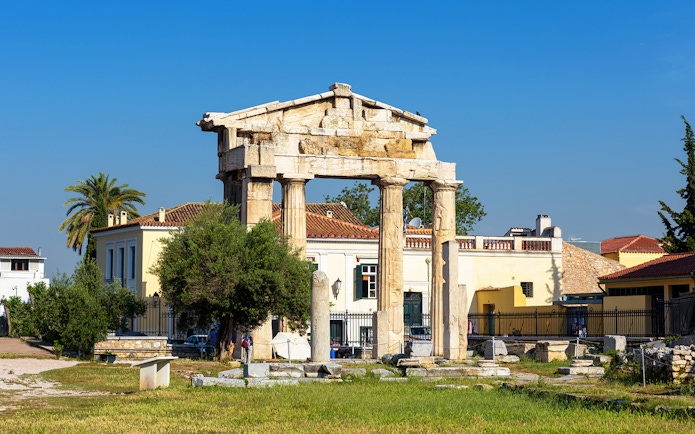 Ancient Greek columns at Roman Agora, Athens with surrounding buildings.